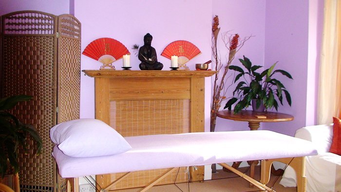 Janet's therapy room: a treatment couch with white towels, a wooden cabinet and a bamboo screen